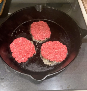 The skillet is heated with one tablespoon of oil over high until smoking. Then, three or four patties are put in and cooked until well browned and crusty on the bottom, about two minutes.