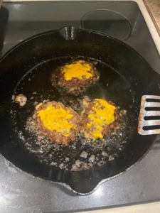 Mustard is spread onto the patty and then turned over so it can cook for one minute.