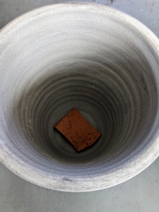 Each pot has a drainage hole. A clay shard is placed over the hole to help prevent any soil from falling out and to aid with drainage.