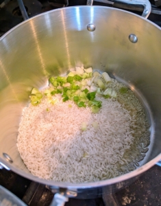 The rice and scallions are heated in a medium saucepan over medium-high heat with a tablespoon of olive oil.