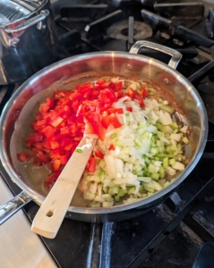 Once the roux is ready, the bell pepper, onion, and celery are added and stirred until softened.