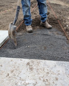 Pete drops stone dust in the path. Stone dust is a non-porous material, which is good to use under stone. It will stop heavy rain water from seeping below and reduces the risk of shifting or damaging the pavers.