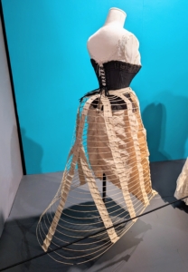 Among the earliest pieces shown are these foundations - a chemise, pantaloons, cage crinoline, and corset from the 1880s, which demonstrate how much the undergarments influenced the overall exterior silhouette of the times. Women were required to dress in these layers in part because corsets were not washable.