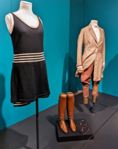 The piece on the left is a bathing suit resembling a simple black dress and bloomers. Fashion designer Coco Chanel often used these styles in her collections - remember her "little black dress," invented in 1926? On the right is a riding ensemble showing how women could wear tailored clothing and trousers during the 1920s. Silent film star and dancer, Irene Castle, wore a riding outfit in the film, Patria.