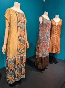 On the left - a simple, loose-fitting dress showing the use of dye resist fabrics. It was not unusual for women in the 1920s to tie-dye their own clothes at home. The other two evening dresses show the use of more luxurious materials and beadwork.