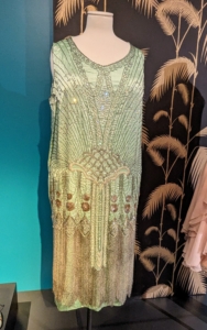 This seafoam green dance dress is made from rayon satin made to imitate silk and last longer than silk chiffons and silks weighted with metallic salts. Made in America, this dress shows the quality of dresses made in the US influenced by World War I and the inability to obtain European garments quickly.