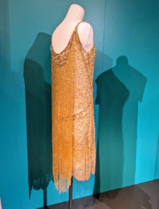 This "Waterfall" dress was likely made in Paris. It features a fringe of beads in back and a base of glass beads and sequins.