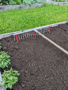 Ryan creates the rows using a bed preparation rake from Johnny’s Selected Seeds. Hard plastic red tubes slide onto selected teeth of the rake to mark the rows.