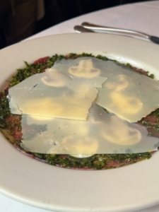 This is Beef Carpaccio, an Italian appetizer of raw beef that's thinly sliced and traditionally served with olive oil, lemon juice, capers, and onions. Elio's serves it with salsa verde.