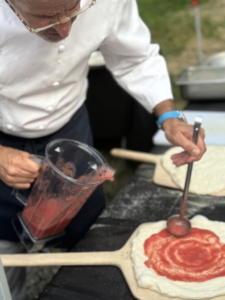 Most of the cooking was done outside. Chef Eyal spreads tomato sauce on the pizza dough.