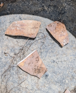 Shards of broken pots are saved and used to cover the drainage holes of the new vessel and prevent soil from spilling out when the plant is watered.