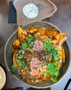 This dish is chilaquiles, or fried tortilla chips, with corn ash, pickled radish, and cilantro. Chilaquiles is a traditional Mexican dish.