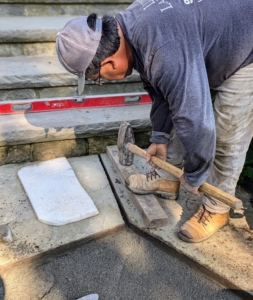 Any repositioned pavers are tamped down with a mallet on a piece of scrap wood, so the stone is not damaged. This packs the stone dust down and sets the paver comfortably and securely in place.