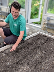 Ryan drops seeds in another bed. These raised beds were designed for easy reach from all sides, so that work can be done quickly and efficiently.