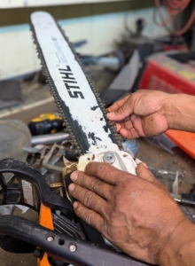 Pasang inspects the teeth and the bar of the chainsaw to see what work needs to be done. This unit needs sharpening.