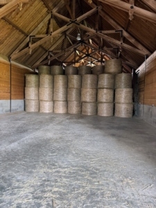 This is inside the restored hay barn notable for its magnificent trusses. Round hay bales are stored in the rear.