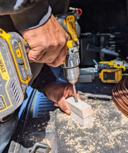 Pete drills a hole through each of the wooden blocks.