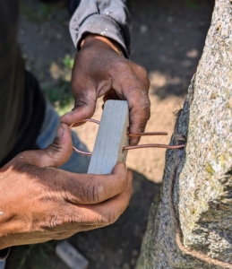 Next, he threads the wire through the second hole in the block.