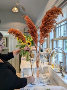 She also holds each stem up to the vase to see where it should be cut to fit. The height of the flowers should be in proportion to the vase's height. A common rule of thumb is that flowers should be one and a half to two times the height of the vase. Enma also cuts them at a 45-degree angle to allow water to flow up into the stem.