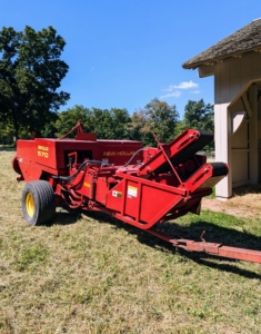 A baler is a piece of farm machinery that compresses the cut and raked crop into compact bales that are easy to handle, transport, and store. The baler is attached to the tractor, and then the hay wagon is attached to the baler.