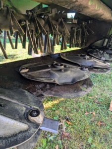 The discs and blades are located behind the protective shield of the mower-conditioner.