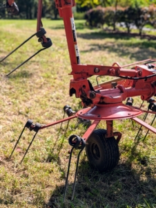 It uses a rotary motion to grab the hay with spinning tines and then cast it out the back of the machine.