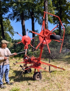 Next, Chhiring washes the tedder. A tedder spreads and fluffs the hay in a uniform swath after the mower-conditioner has cut the hay.