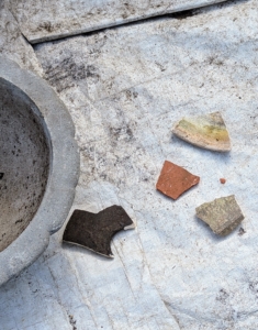 To prepare the pot for planting, Ryan first covers the drainage hole with a shard. I save all clay shards from broken pots so they can be repurposed in this way.