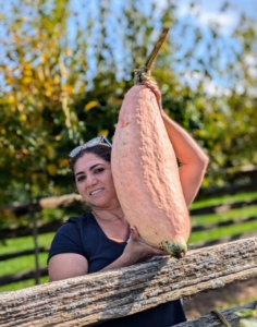 Enma is holding a giant pink banana squash - it's about two feet long!