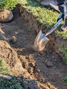 José removes any excess soil and manually smooths out the trench as needed. He also removes any rocks that would be in the way.