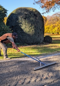 Here, Pete uses a landscape rake to spread and level the gravel to the edges of the road. This area is also high traffic, so it needs extra attention.