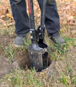 In assembly line fashion, Cesar begins making holes with a post hole digger.