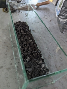 Ryan pours an even layer into the container over the gravel.