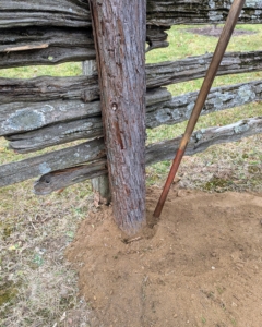 Once backfilled, Pete uses a tamping bar to pack the soil tightly around the post.