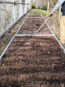 Ryan rakes over the furrows to ensure all the seeds are covered. He will also give them a good drink. Rain, snow, and condensation should keep the soil moist through the cold season, And then come spring, we should have beautiful flowers growing right here.