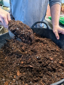 Because there are so many plants to repot, Ryan adds another three bags of each potting mix to the bucket.