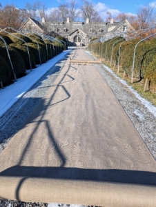 The fabric is unrolled along the allée and prepared for sewing.