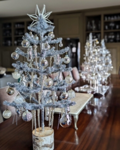 I try to vary the holiday decorations in my home. I always use lots of trees – silver, green or gold in every room. And I always try to display them differently each time. In my Brown Room, silver trees decorate the dining table with ornaments and glass icicles on every branch.