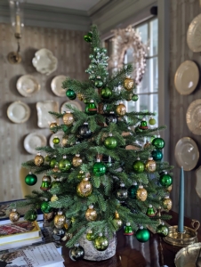 Here is a green tabletop tree in my sitting room. The ornaments include different shades of green and gold.