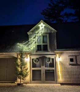 And outside, I take out several shooting stars and hang them on some of the outbuildings here at the farm. Here's a tip: if one needs to use extension cords to connect outdoor decorations, use supplies that match the exterior of the building. I use grayish-tan extension cords, so they are not seen against the siding. Also be sure any electrical supplies are safe to use outside.