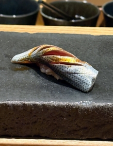 This is called Kohada, or gizzard shad, a silver-skinned fish. It is served with nikiri soy sauce.