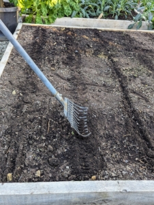 Ryan backfills the furrows to cover the seeds in each filled row. He also leaves some rows empty, so he can plant more in a few weeks. Lastly, every bed will get a good drink of water.