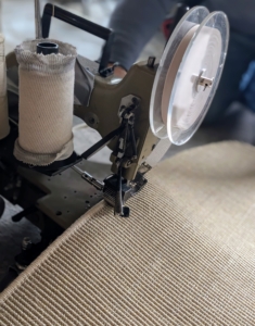 The matching colored yarns are placed on spools and the machine wraps the threads over the edges.