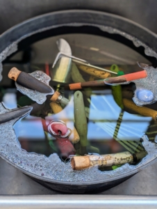 Hand tools such as dibbers, scoops, and small rakes were placed in a trug bucket and soaked for several minutes in warm, soapy water to loosen any dirt. Regular dish soap can work.