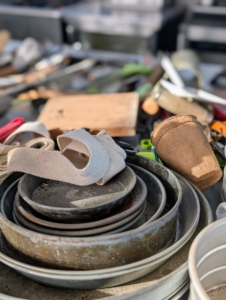 Here are miscellaneous metal drainage saucers, seed starting cups, and pot straps on another table. Ryan separated items that needed cleaning from those that just needed re-organizing.