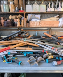 Every table surface of my head house was covered with tools and supplies. These are all watering wands, hose nozzles, and various shears.