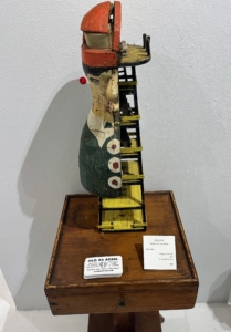 This piece was shown by Adam Irish, Antiques & Americana. The designer is unknown and shows a half man - half lighthouse wooden sculpture.