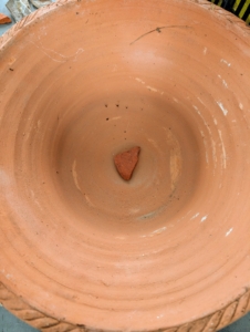 I always place a shard over the hole of the pot to help with drainage and to prevent soil from falling through.