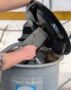 The filter is connected to a tray that sits on top of the tank. Ryan fills the brewing tank with potable water up to the fill line.