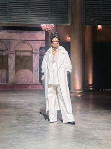 The evening continued with a runway show of Sabyasachi's designs. Deepika Padukone opened with a monochromatic and elegant white ensemble, a flowing trench coat, several necklaces, and a cross pendant.